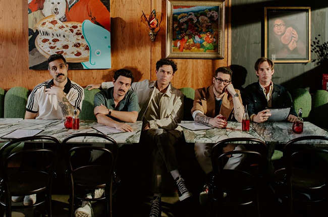 Members of the band Arkells sitting at a table.