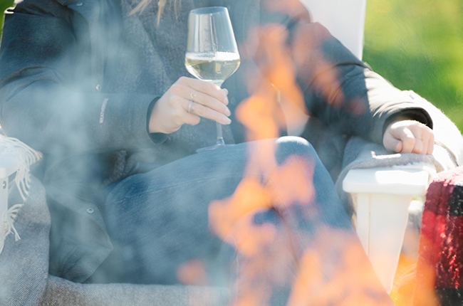 A woman enjoying a wine tasting by a firepit at 13th Street Winery.