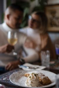 A couple in the background of a shot of a table with a streusel on a plate.