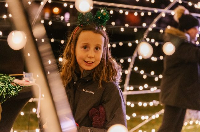 A smiling child enjoying the Let it Glow - A Celebration of Light festival in St. Catharines.